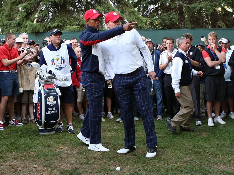 Tiger Woods offers advice after his tee shot on the first ends up in the rough.