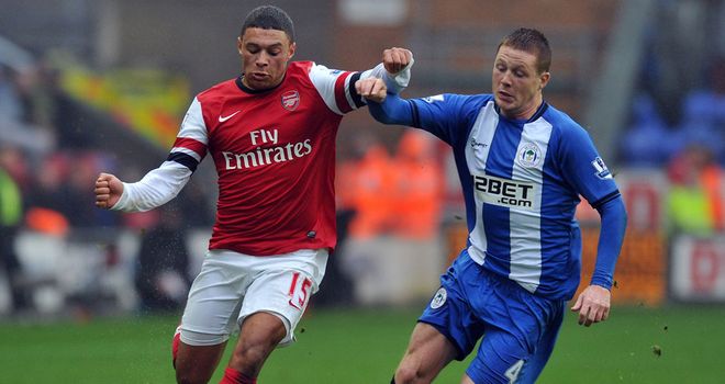 Alex Oxlade-Chamberlain (left) holds off Wigan's James McCarthy