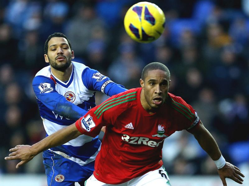 Swansea captain, Ashley Williams is challenged by Reading skipper Jobi McAnuff