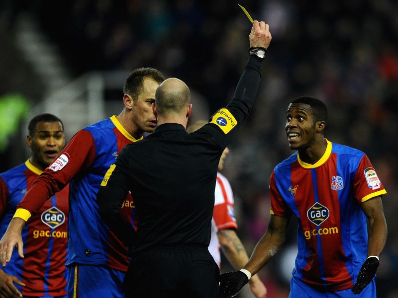 Wilfred Zaha is shocked after being booked for diving by referee Anthony Taylor