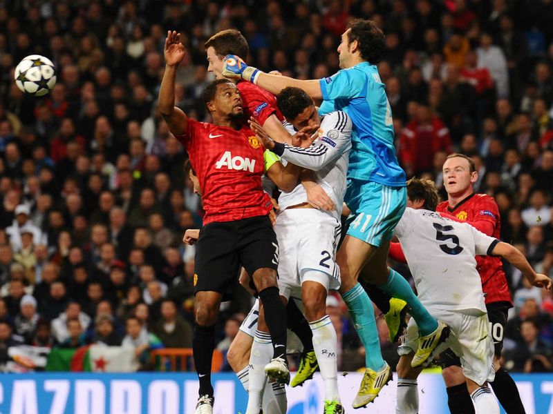 Real Madrid goalkeeper Diego Lopez punches the ball away under pressure from Manchester United players