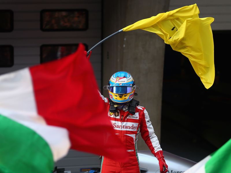 Fernando Alonso celebrates on top of his car with a Ferrari flag