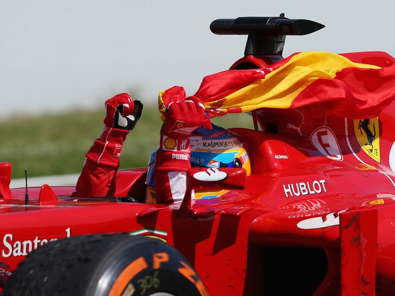 Fernando Alonso laps the track with the Spanish flag