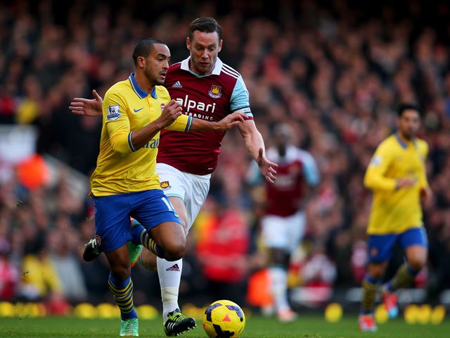 Theo Walcott and Kevin Nolan battle for the ball