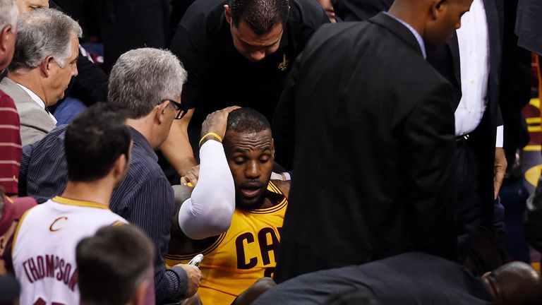LeBron James holds his head after falling into the media in the second quarter