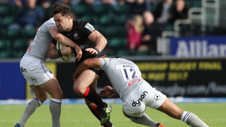 Brad Barritt of Saracens is tackled by Bath's George Ford (L) and Ben Tapuai