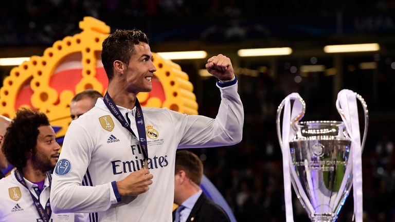 The Real Madrid forward celebrates next to the Champions League trophy