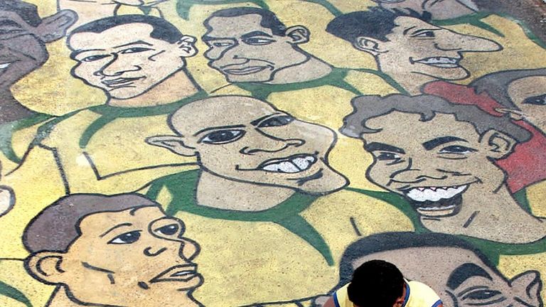 A man puts finishing touches to street art featuring the Brazil football team