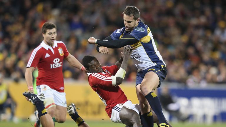 Christian Wade of the Lions is tackled by Matt Toomua and Andrew Smith (R) of the Brumbies at Canberra Stadium