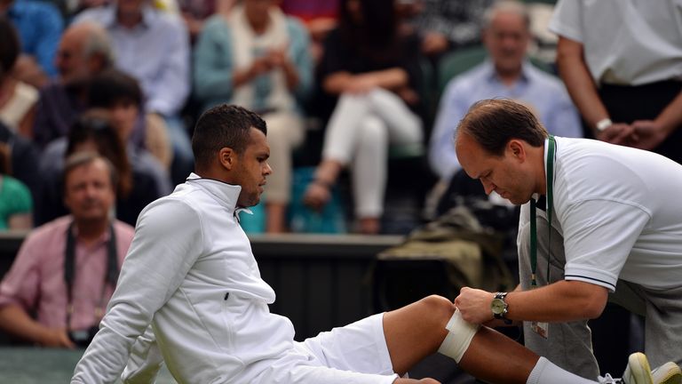 France's Jo-Wilfried Tsonga recieves attention to his leg during a medical time out in his match against Latvia's Ernests Gulbis during their second round men's singles match on day three of the 2013 Wimbledon Championships tennis tournament at the All England Club in Wimbledon, southwest London, on June 26, 2013