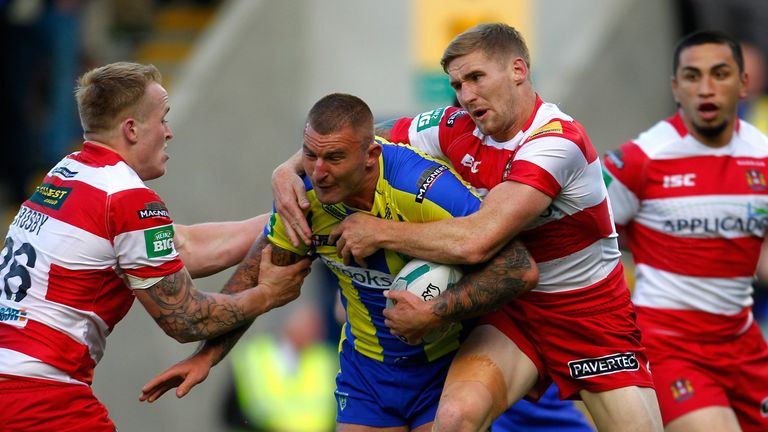 Paul Wood of Warrington (C) is tackled by Sam Tomkins of Wigan during the Super League match at the Halliwell Jones Stadium