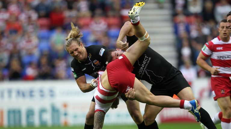 Huddersfield Giants' Eorl Crabtree (right) and Brett Ferres tackle Wigan Warriors' Josh Charnley (centre) during a Super League match at the DW Stadium.