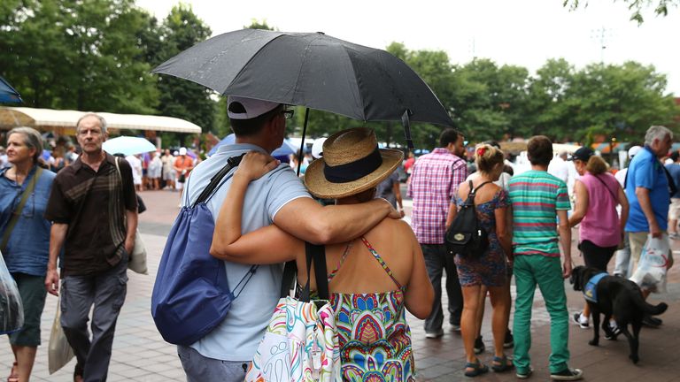 Tennis fans shelter under umbrellas as rain interrupts play during day three of the 2013 US Open at USTA Billie Jean King National Tennis Center in New York