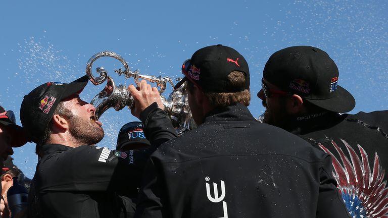 Oracle Team USA tactician Sir Ben Ainslie  (L) drinks champagne from the America's Cup trophy as he celebrates onstage after they beat Emirates Team New Zealand to defend the America's Cup during the final race on September 25, 2013 in San Francisco, California.  