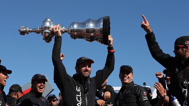 Oracle Team USA tactician Sir Ben Ainslie  (C) holds the America's Cup trophy as he celebrates onstage after they beat Emirates Team New Zealand to defend the America's Cup during the final race on September 25, 2013 in San Francisco, California.