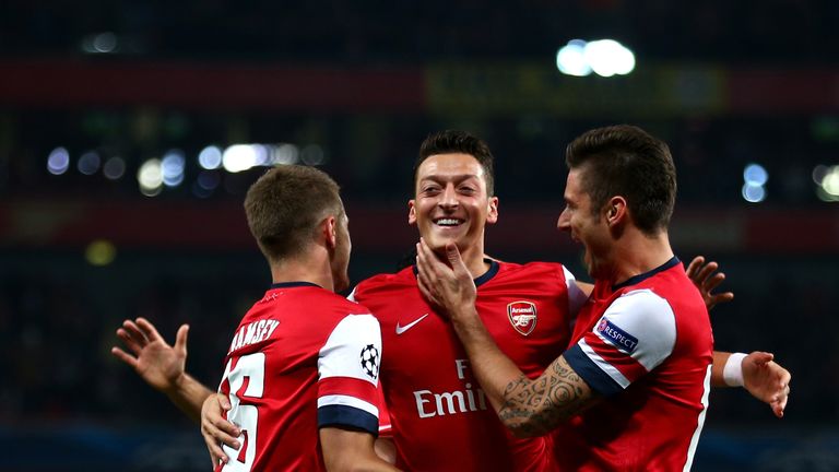 Mesut Ozil (C)of Arsenal is congratulated by teammates Aaron Ramsey (L) and Olivier Giroud (R) after scoring the opening goal during UEFA Champions League Group F match between Arsenal FC and SSC Napoli at Emirates Stadium 