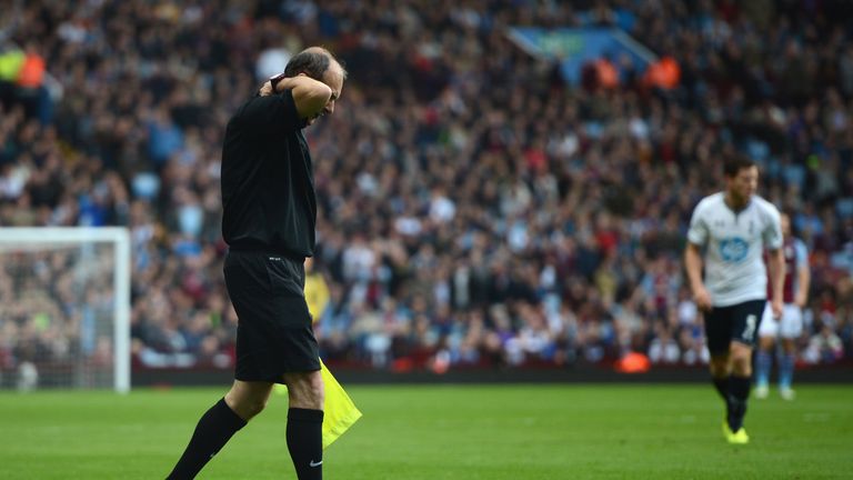 Referee's assistant David Bryan clutches his shirt after he was hit by a smoke bomb thrown from the crowd following Andros Townsend's opener at Villa Park.