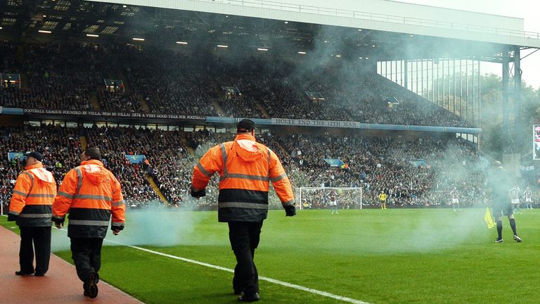 Referee's assistant David Bryan steps onto the pitch after getting hit by a smoke bomb thrown after Tottenham scored a goal during the Premier League football match between Aston Villa and Tottenham Hotspur at Villa Park.
