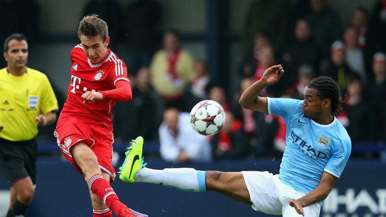 Michael Eberwein of Bayern Munich shoots as Jason Denayer of Manchester City tries to block during the UEFA Youth Champions League match at Ewen Fields on October 2, 2013 in Manchester