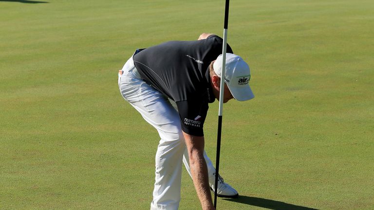 Jamie Donaldson retrieves his ball from the hole at the par 3, 16th hole after making a hole in one during the final round of the 2013 Turkish Airlines Open