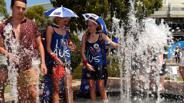 Tennis fans take a dip in a fountain to cool off from the heat on day four of the 2014 Australian Open tennis tournament in Melbourne on January 16, 2014. 