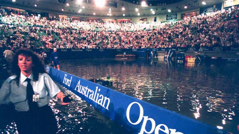 A security guard removes people from the centre court, which flooded at the 1995 Australian Open