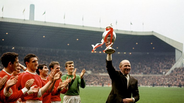 Manchester United manager Matt Busby (r) holds the League Championship trophy aloft as his players applaud: (l-r) Shay Brennan, Bill Foulkes, Tony Dunne,