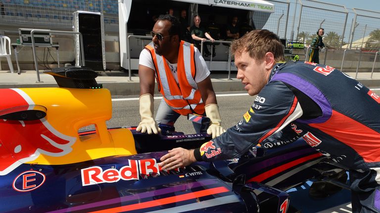 Sebastian Vettel pushes his car back along the pitlane