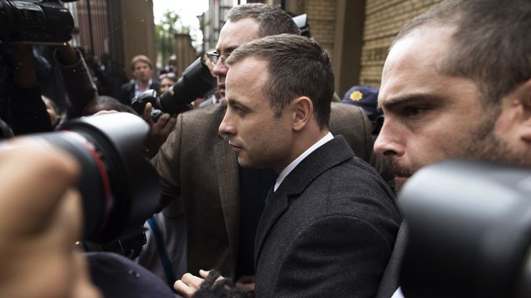 South African Paralympic athlete Oscar Pistorius is escorted outside the courtroom followed by a pack of  journalists on March 4, 2014