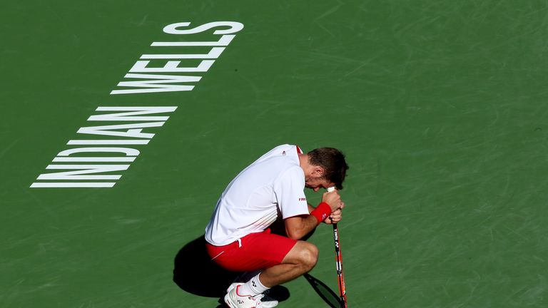 Stanislas Wawrinka kneels on the court after receiving treatment from a trainer during his match against Kevin Anderson at BNP Paribas Open