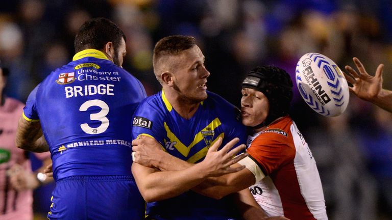 Ben Currie of Warrington offloads under pressure from Jonny Lomax of St Helens during the Super League match  at the Halliwell Jones Stadium.