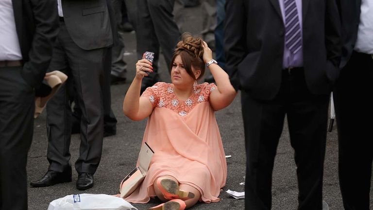 A racegoer uses the camera on her phone to check her hair at Aintree