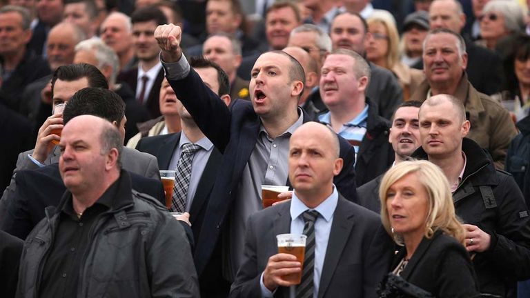 A man cheers on his horse as racegoers attend the opening day of the Grand National Festival at Aintree Racecourse on April 3