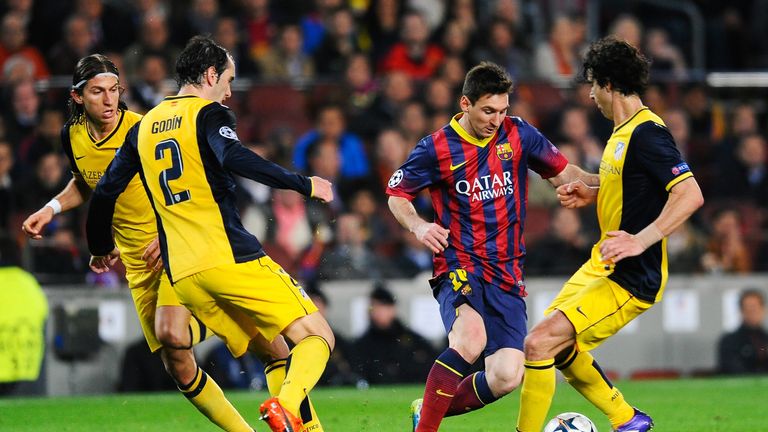 Lionel Messi of Barcelona takes on (L-R) Filipe Luis, Diego Godin and Tiago of Atletico Madrid
