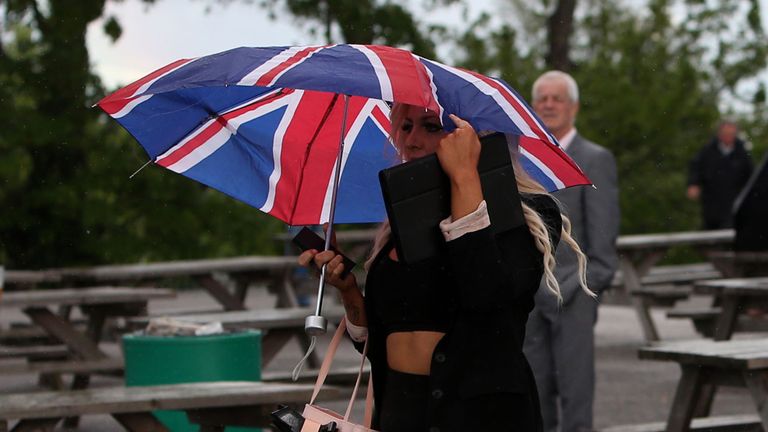 A racegoer battles the wind and rain at Sandown.