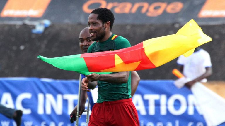 Cameroon forward Jean Makoun holds a flag as he celebrates his team's qualifcation for the 2014 FIFA World Cup in Brazil