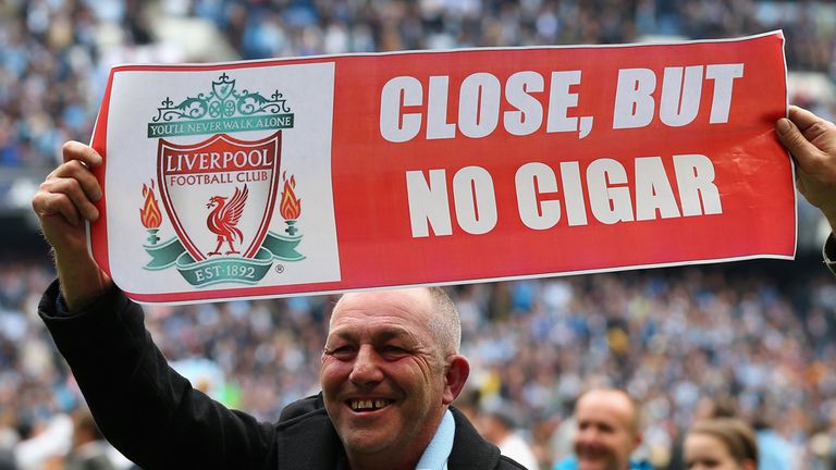 A Manchester City fan shows off a banner mocking Liverpool 