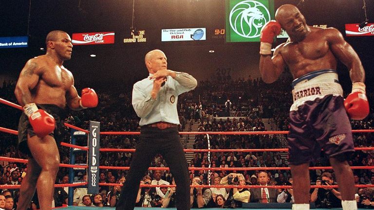 Referee Lane Mills (C) stops the fight in the third round as Evander Holyfield (R) holds his ear against Mike Tyson (L)