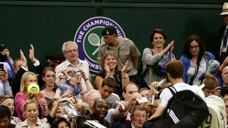 Andy Murray signs autographs as he walks off court following his victory against Tommy Robredo