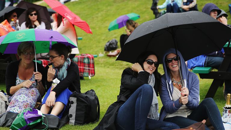 LONDON, ENGLAND - JUNE 27:  Fans shelter under umbrellas as rain delays play on day five of the Wimbledon Lawn Tennis Championships at the All England Lawn