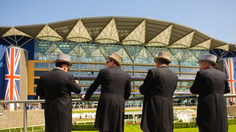 Racegoers in morning suits overlook the parade ring and grandstand at Royal Ascot Meeting