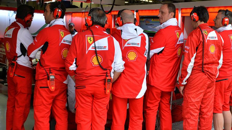 Ferrari mechanics shield the Ferrari F14 T in the garage..