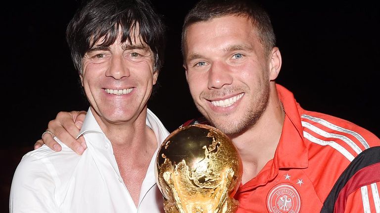 Joachim Loew (l) and Lukas Podolski pose with the World Cup trophy