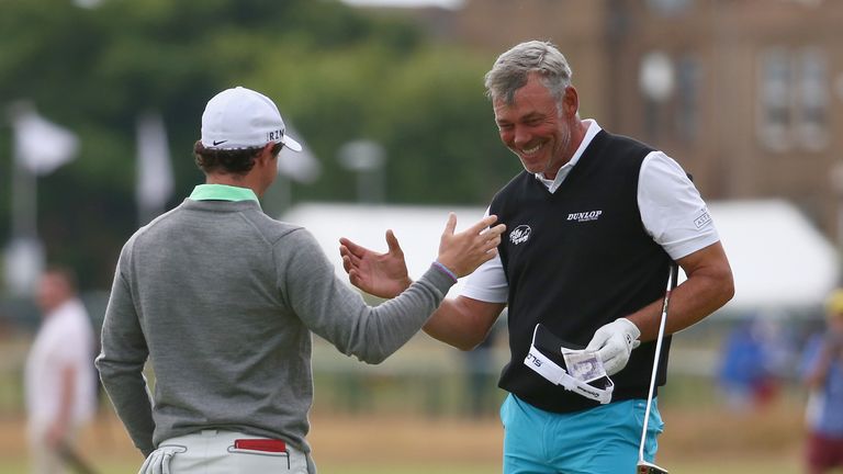 HOYLAKE, ENGLAND - JULY 16:  Rory McIlroy (L) of Northern Ireland takes a bank note in celebration of winning a bet against Darren Clarke (R) after their p
