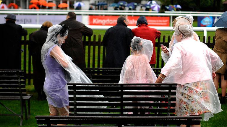 Racegoers wear rain covers as the rain falls at Newmarket 