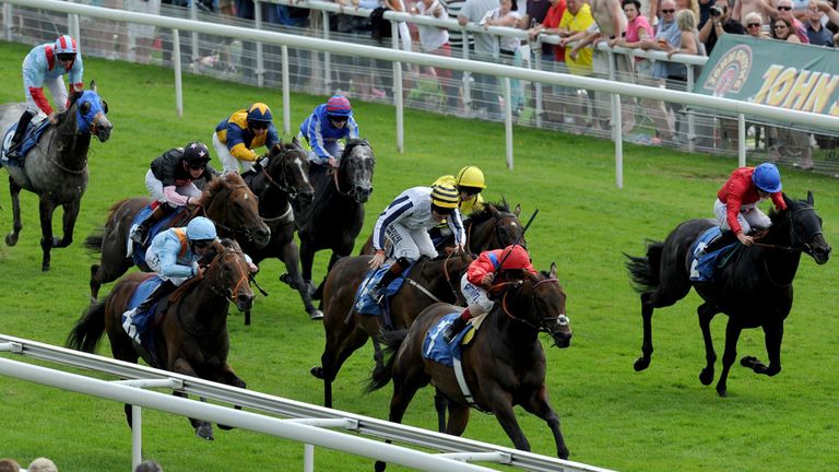 Take Cover ridden by Andrea Atzeni (centre, red silks) wins the John Smith's City Walls Stakes during the 55th John Smith's Cup day at York.