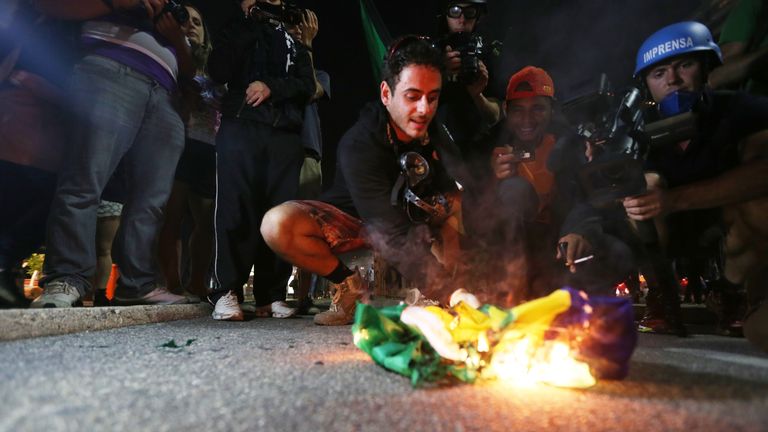 RIO DE JANEIRO, BRAZIL - JUNE 12:  A protestor burns a flag during an anti-World Cup demonstration in the Copacabana section on June 12, 2014 in Rio de Jan