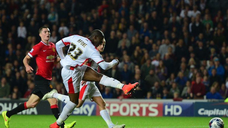 MK Dons English striker Benik Afobe scores their fourth goal during the English League Cup second round football match between Milton Keynes Dons and Manch
