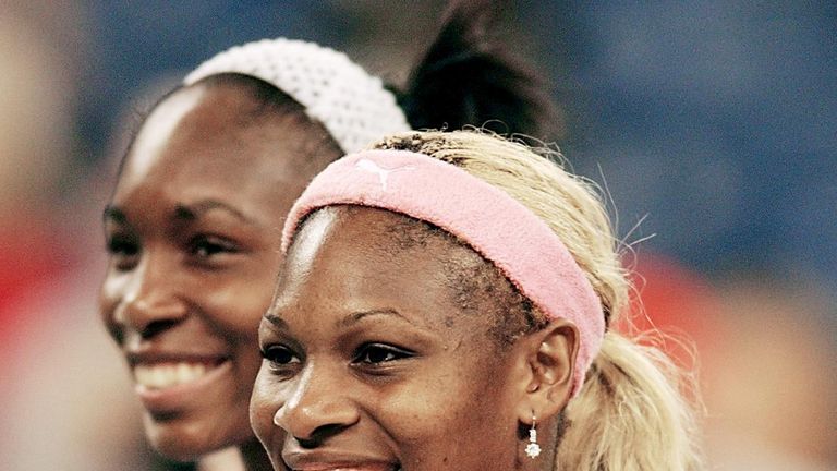 Serena Williams (R) displays the US Open Women's Singles trophy after defeating her sister Venus Williams in the 2002 final