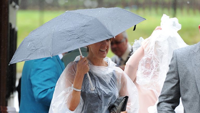 Racegoers arrive during a rain shower, on Ladies Day during Day Two of the 2014 Welcome To Yorkshire Ebor Festival at York